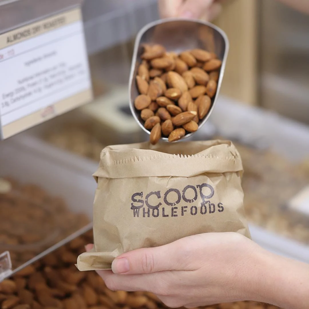 Almonds scooped into a Scoop Wholefoods paper bag